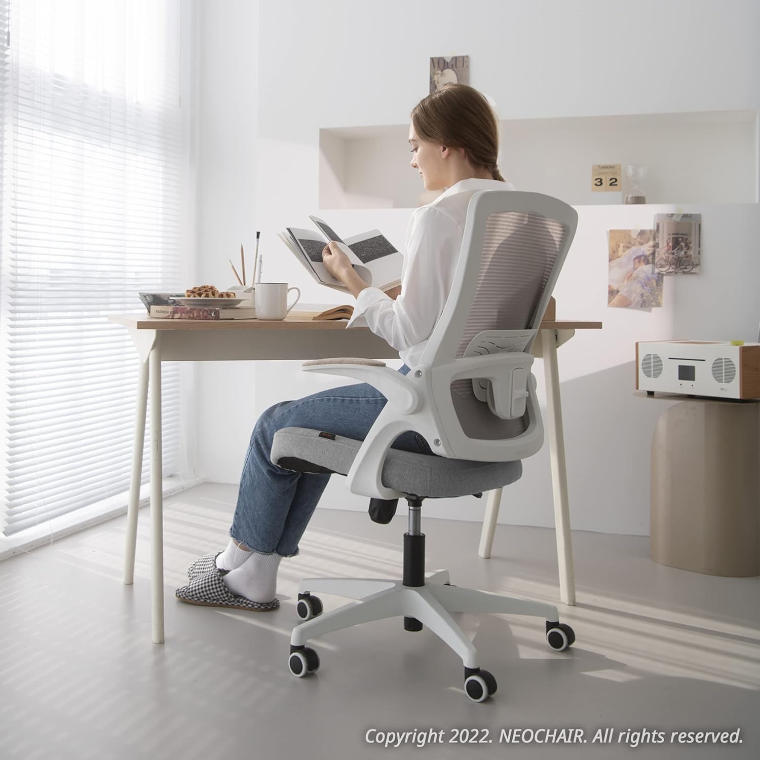 White Desk Chair being used by a woman reading a book.