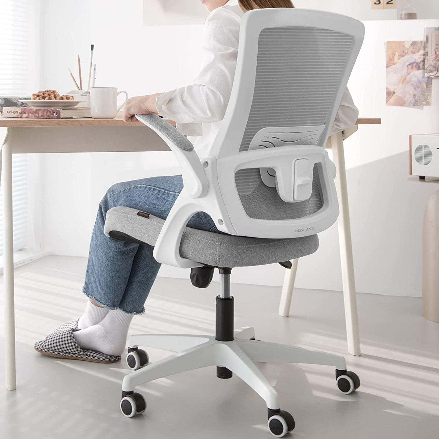 White Desk Chair being used by a person with a desk in front.